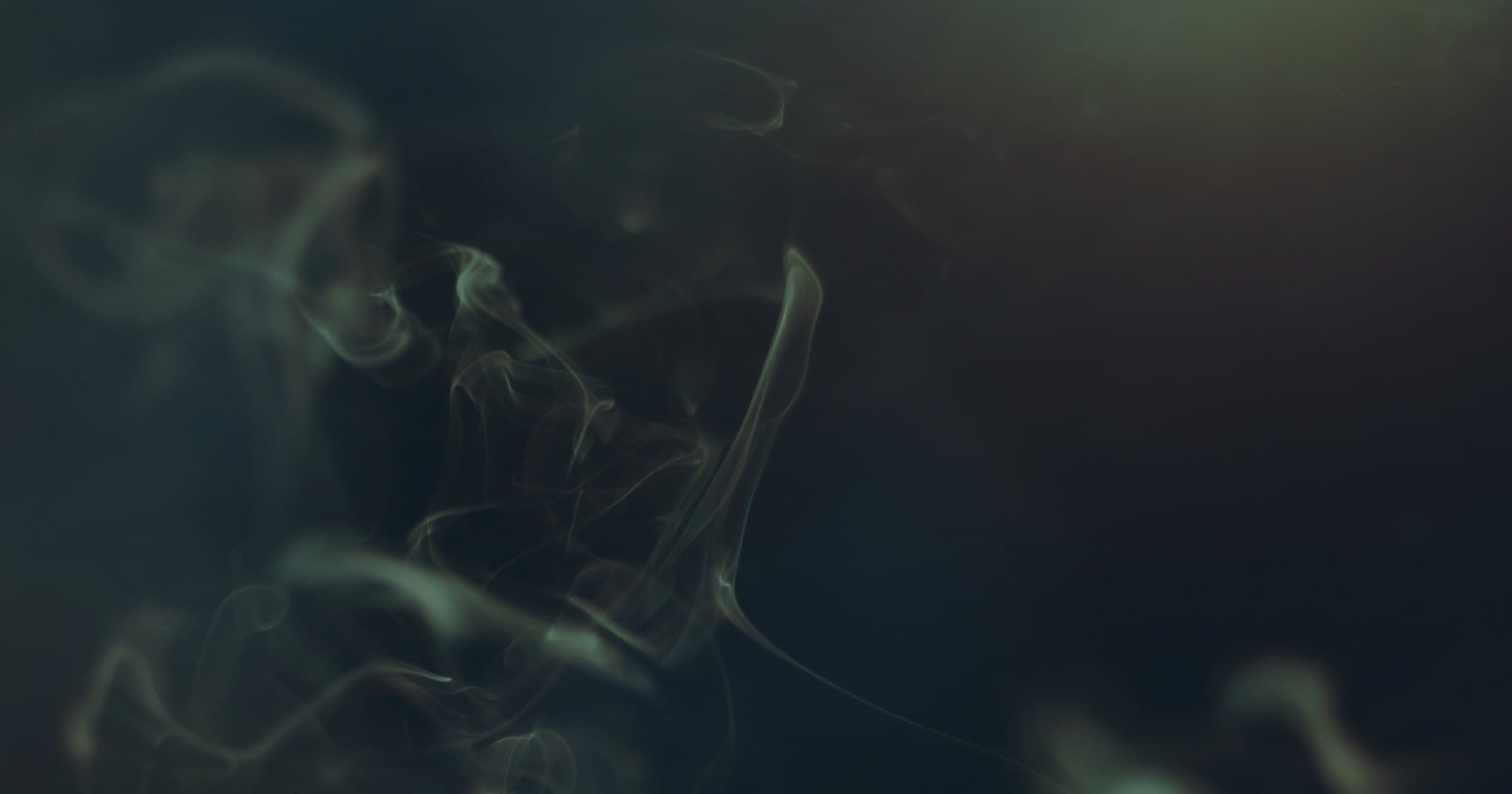 Fine wisps of smoke curling against a dark ground.