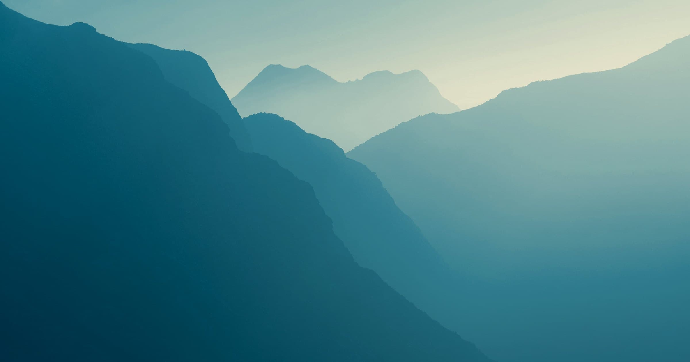 Layered mountain ridges receding into morning haze.