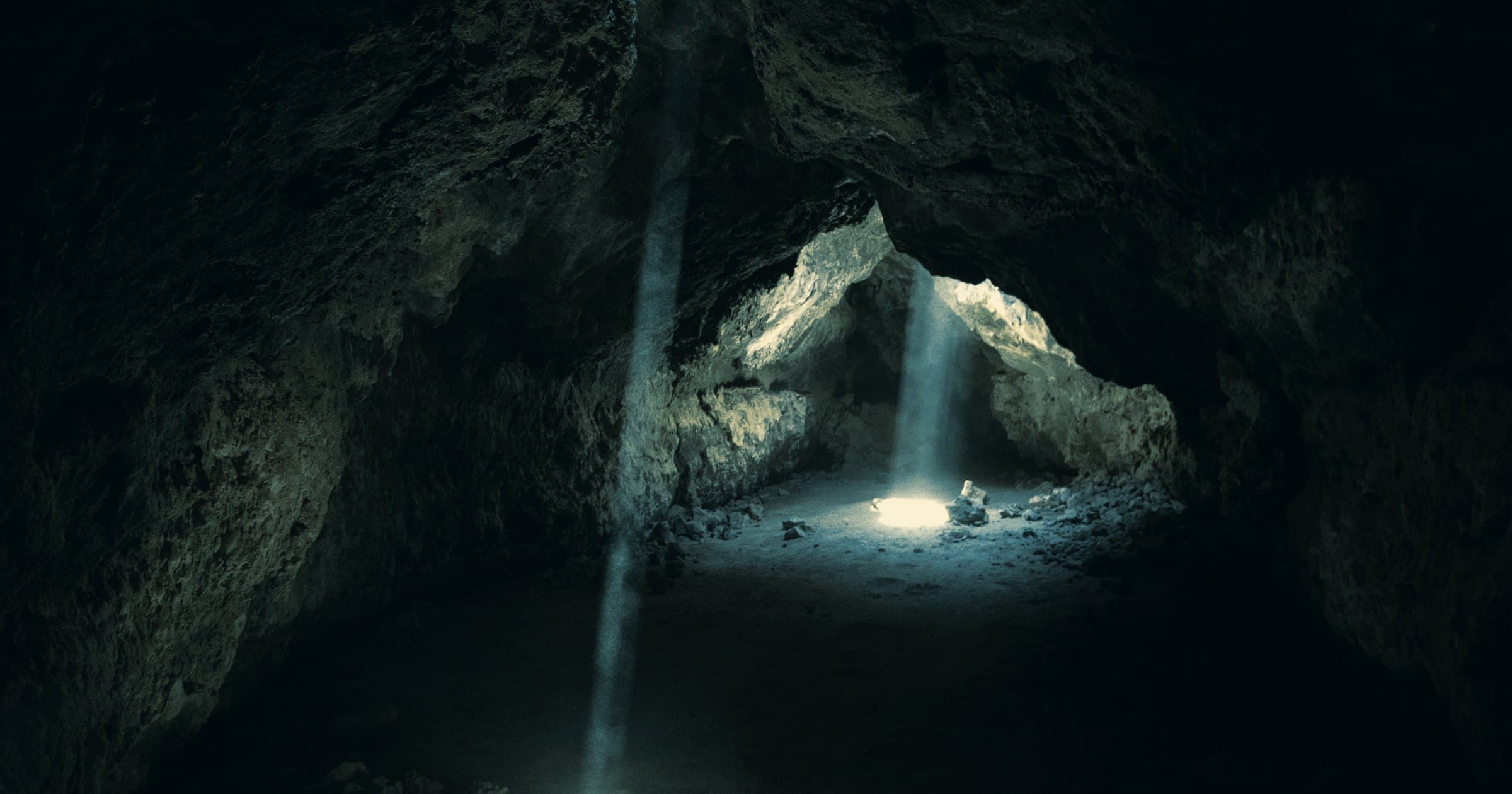 Daylight falling through the mouth of a cave onto the floor below.